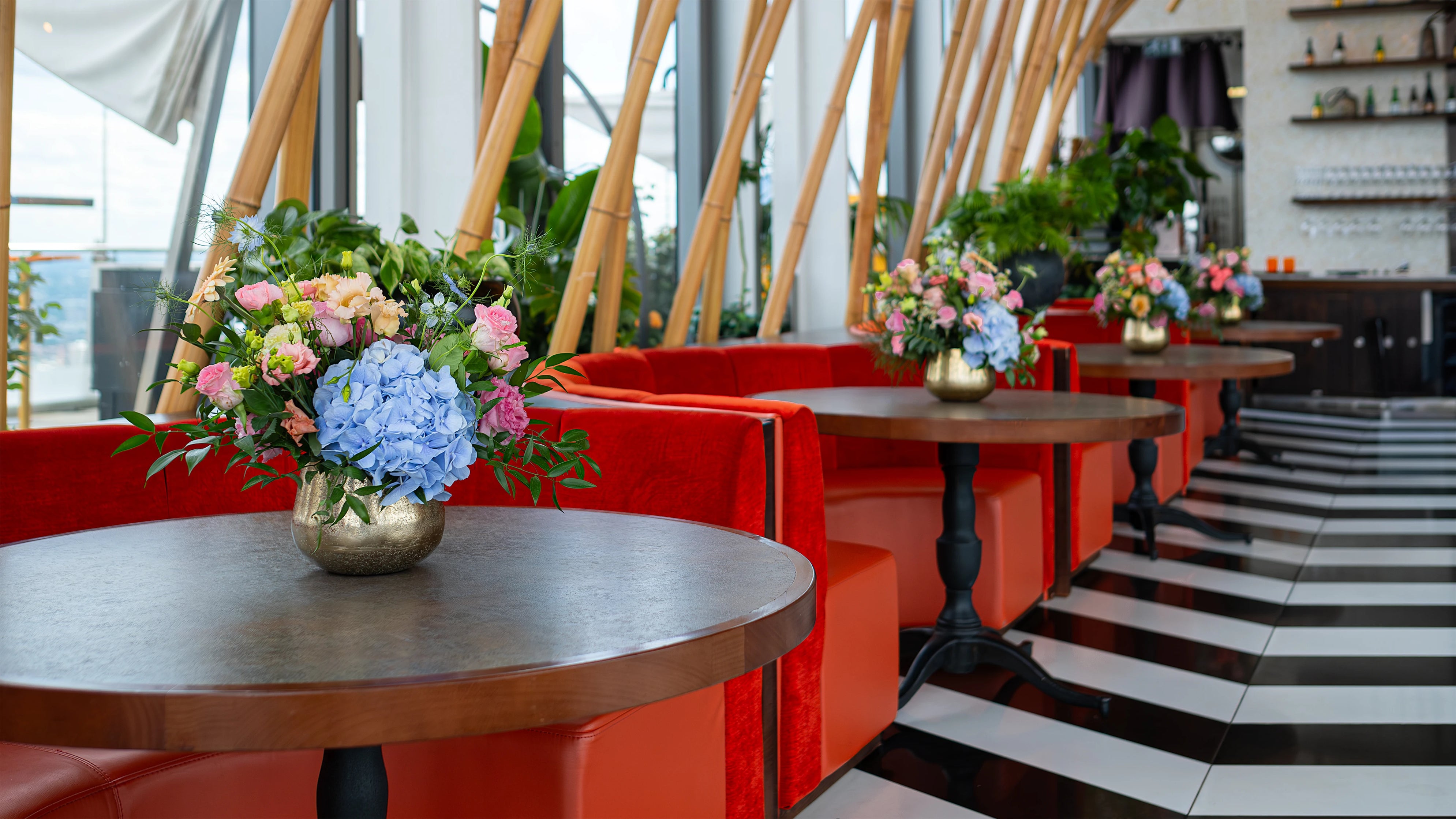 A stunning floral party decoration designed by event florist Amarante London was placed on a bar at Sushi Samba for a birthday event. It featured pink and peach roses, blue hydrangeas, and lush greenery, adding a sophisticated and celebratory vibe to the space.