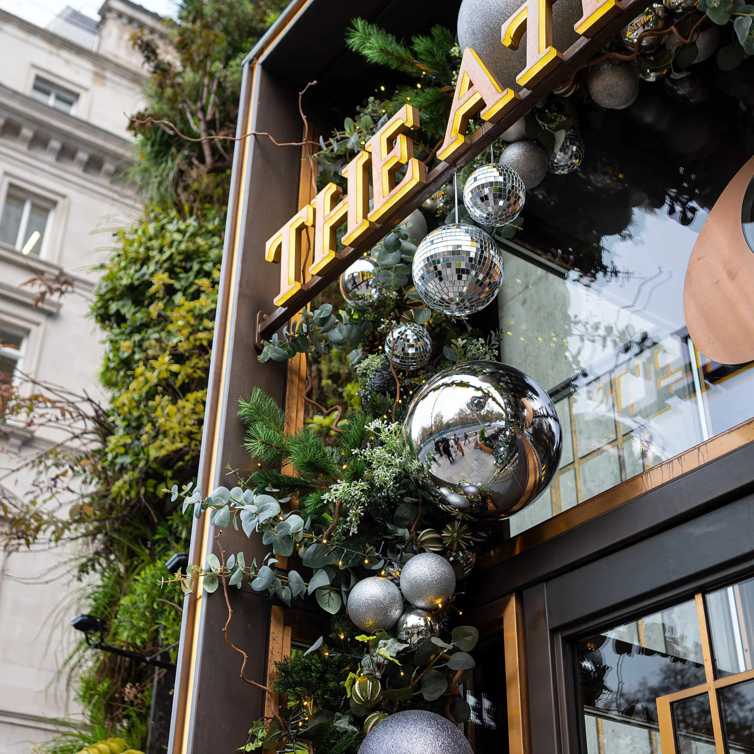 The exterior of 'The Athenaeum' hotel is festively adorned by a bespoke floral arrangement designed, produced and installed by Amaranté London. A custom-designed floral installation, featuring a luxurious mix of pine greenery, eucalyptus, and shimmering silver and mirrored disco ball ornaments, which tastefully embellish the golden signage, inviting guests into a world of festive luxury.