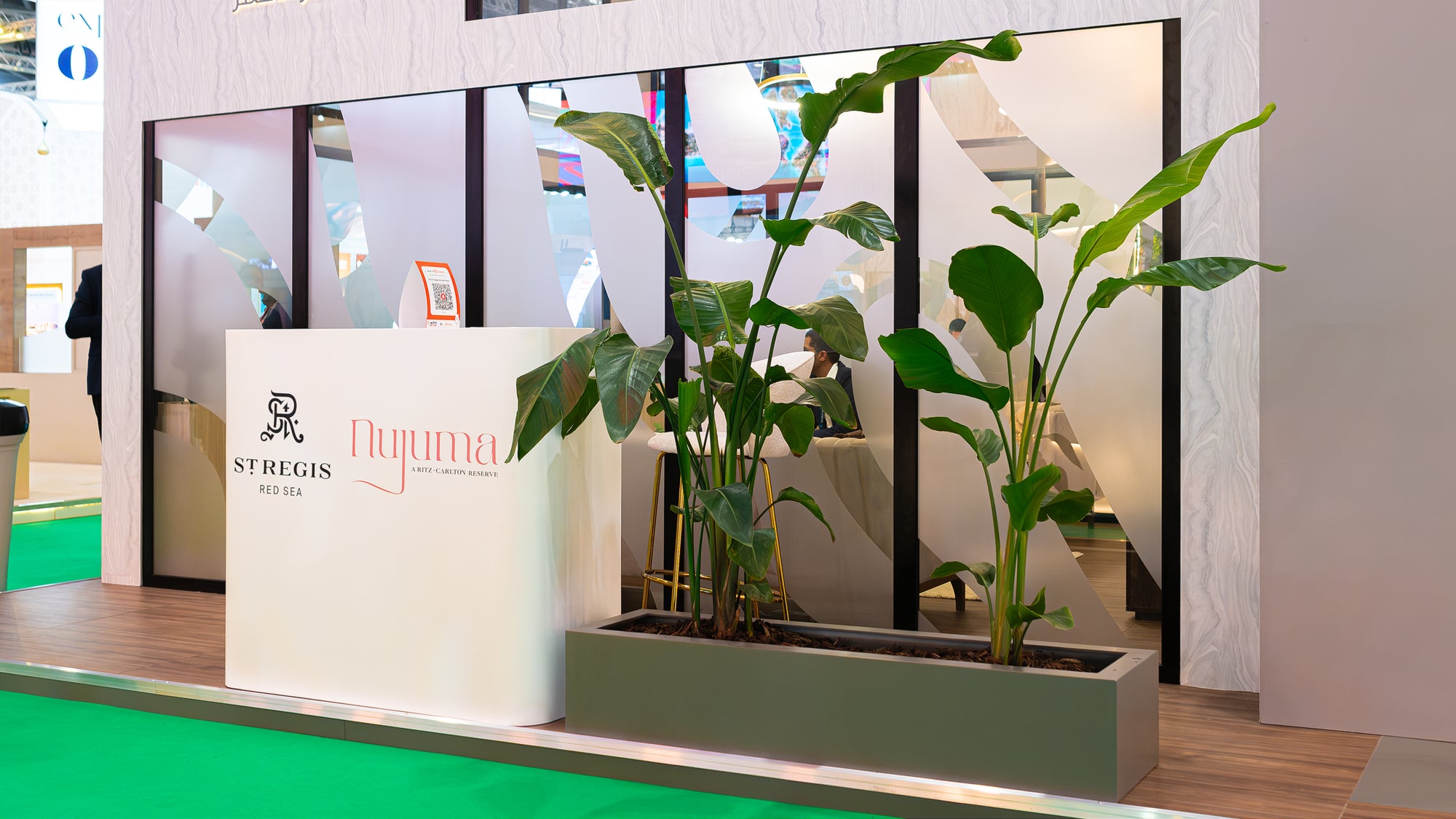 Minimalist event space at WTM London highlighted by bold green plants in sleek planters, reflecting the sustainable luxury promoted by Red Sea Global - Amaranté London.