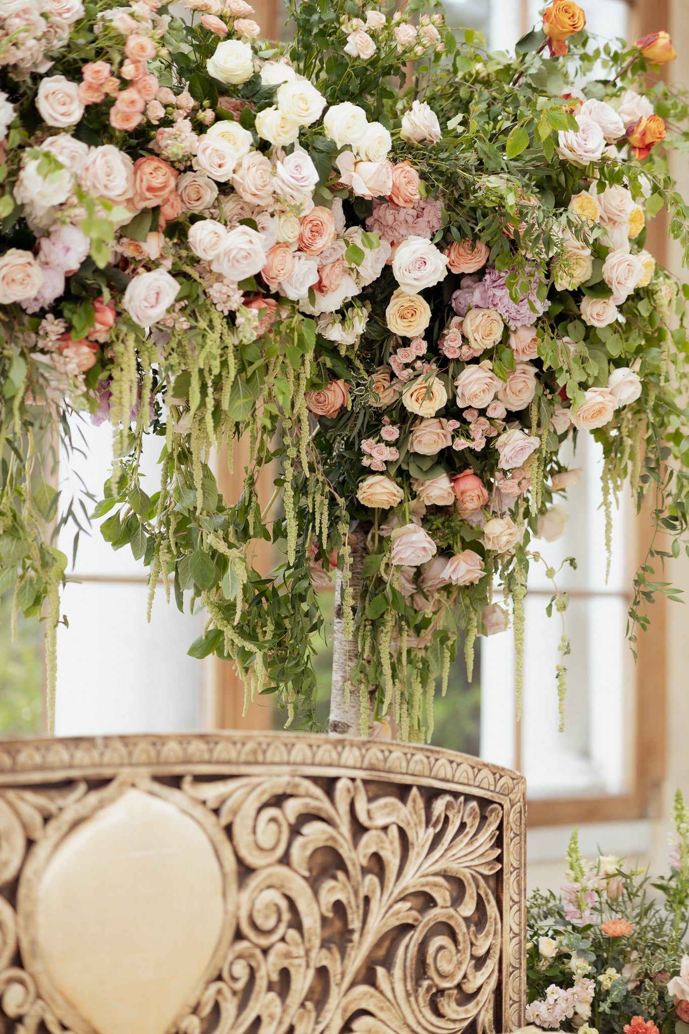 Detailed view of cascading floral ceiling installation featuring blush and white roses with trailing greenery above ornate furniture - Amaranté London