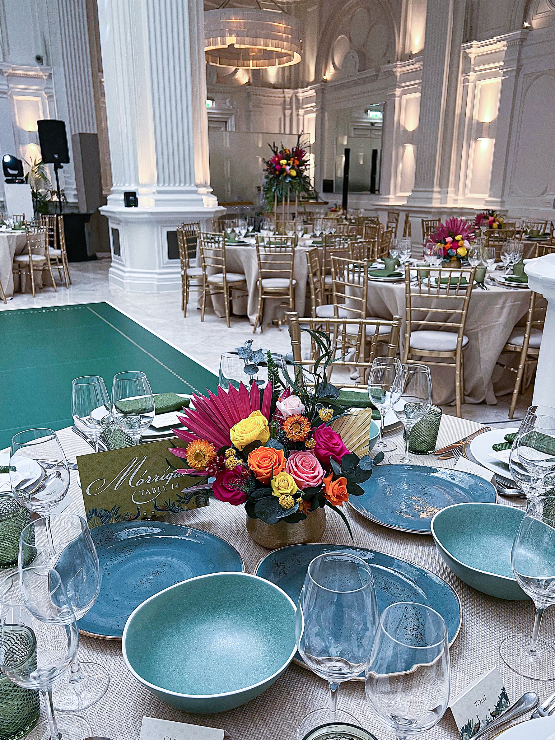 Casual dining setup with natural wildflower arrangements in glass vases on sage green linens in a bright restaurant setting - Amaranté London Event Florist