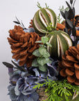 Decorative arrangement with pinecones, pumpkins, and hydrangeas on a white background