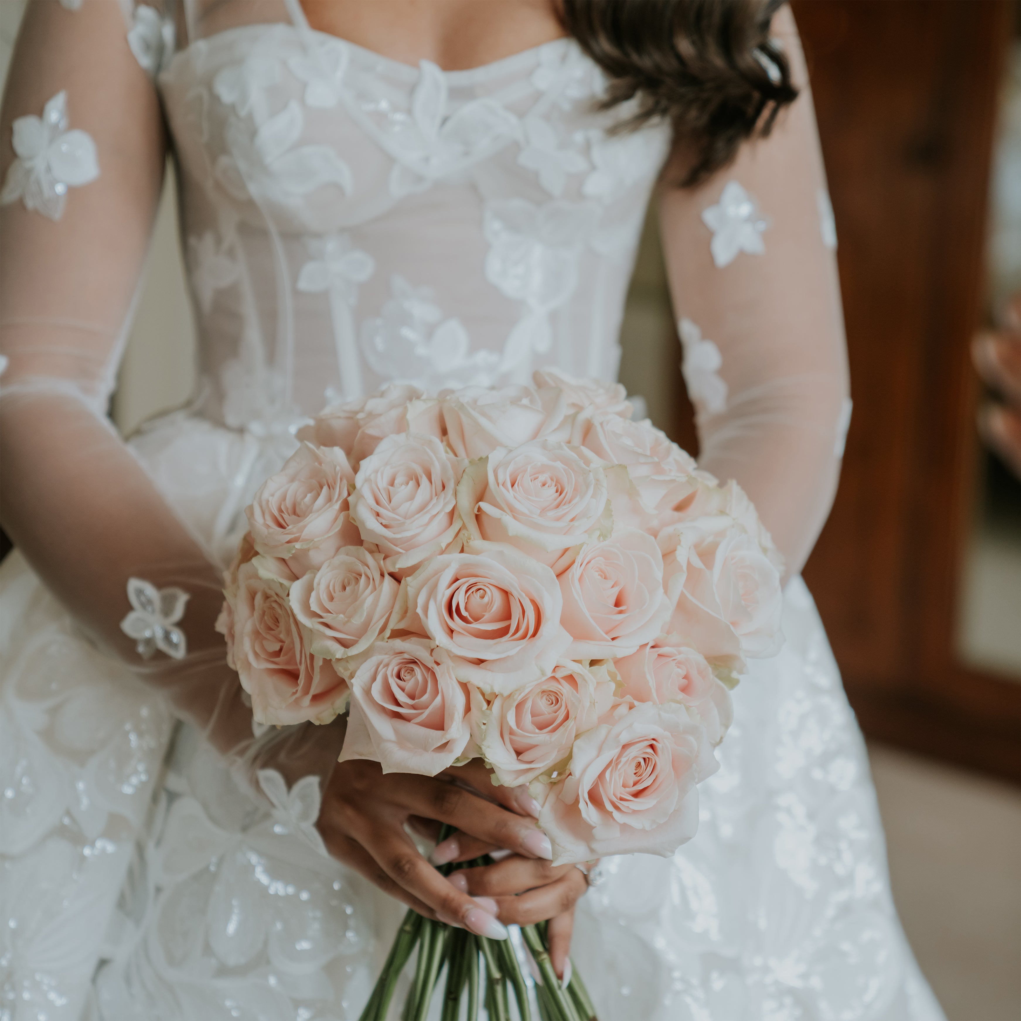 Bride holding an elegant bouquet of blush pink roses wrapped with ribbon at Hampton Court Castle wedding - Floral Design by Amaranté London.