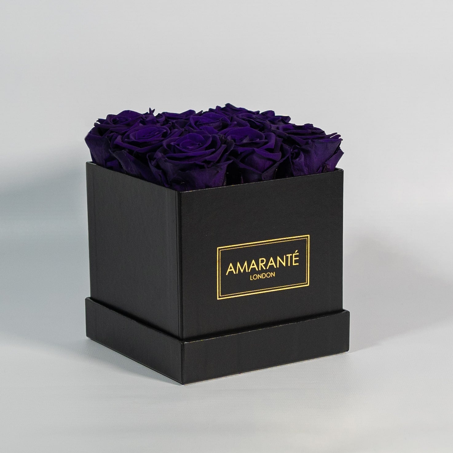 Enchanting dark purple roses encompassed in a modern black box 