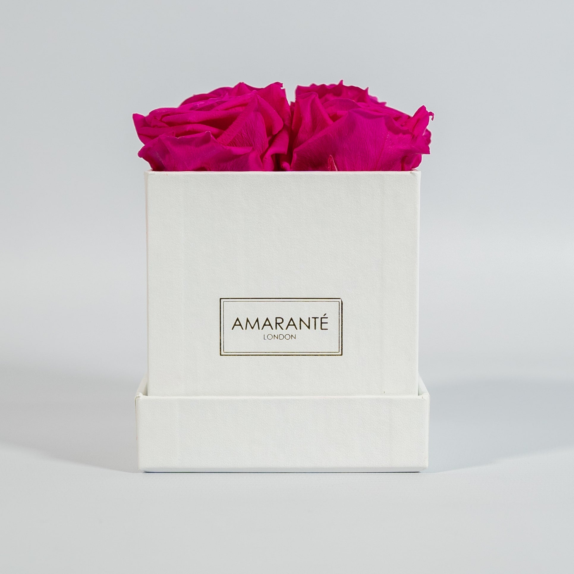 Distinctive hot pink roses displayed in a fashionable white box 