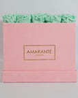 Earth toned mint green roses shown in a sleek pink box 