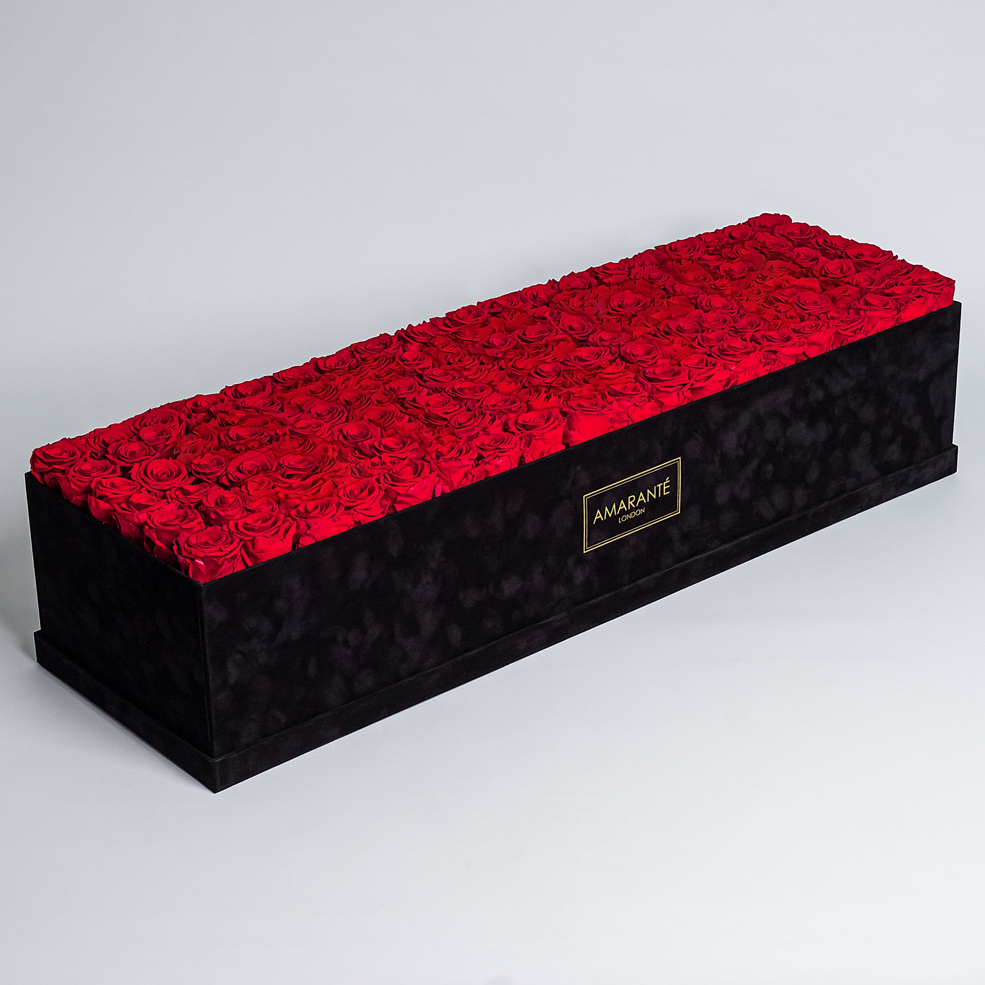 Sophisticated 100cm x 30cm black rectangular suede rose box containing 140 large infinity roses with optional custom message spelled out in contrasting rose colours, luxury Valentine's gift that lasts up to three years - Amaranté London.