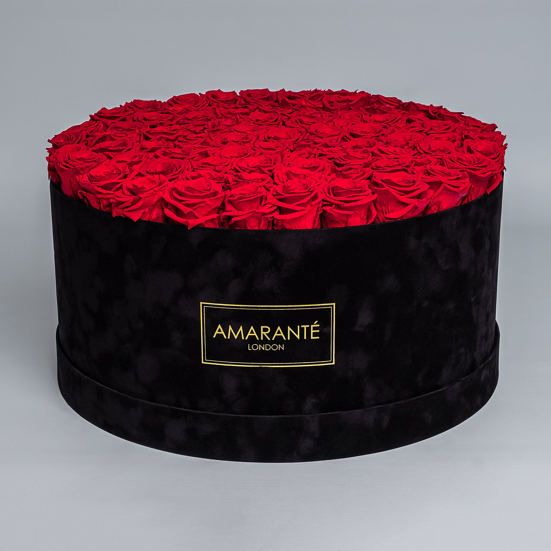 Mesmerising 20-inch round black suede rose hatbox filled with 100 infinity roses in classic red, luxury Valentine's roses that last up to three years with proper care, elegant gift presentation - Amaranté London.