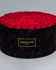 Mesmerising bouquet of 100 light red infinity roses nestled in a black round rose box with delicate suede finish. Exquisite gift for showing timeless love and affection. FreeUK Delivery.