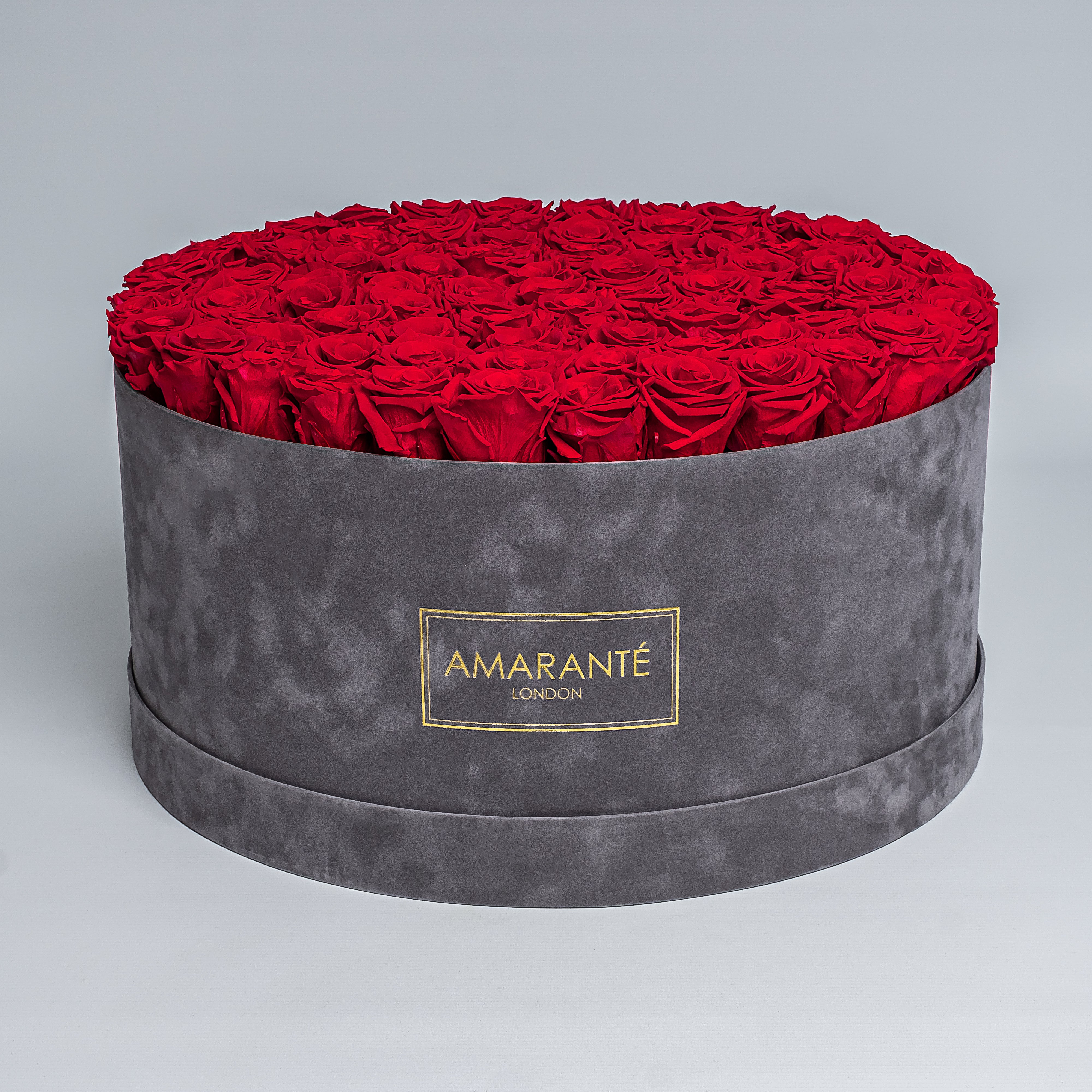 Mesmerising bouquet of 100 light red infinity roses nestled in a grey round rose box with delicate suede finish. Exquisite gift for showing timeless love and affection. FreeUK Delivery.