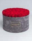 Elegant light red Infinity Roses artistically arranged in a trendy round grey suede rose box. This mesmerising, luxurious gift can be delivered for free in the UK, perfect for showing timeless love and affection to family, friends, or your significant other.