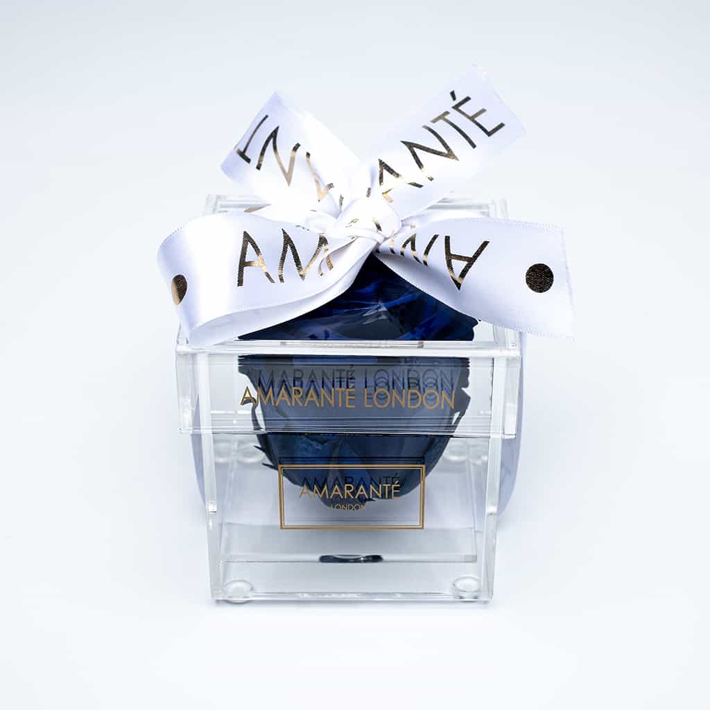 Royal Blue Infinity Rose in transparent acrylic box decorated with a white ribbon - a unique symbol of love and affection to celebrate Valentine&#39;s Day and other memorable romantic events with a touch of elegance and sophistication.