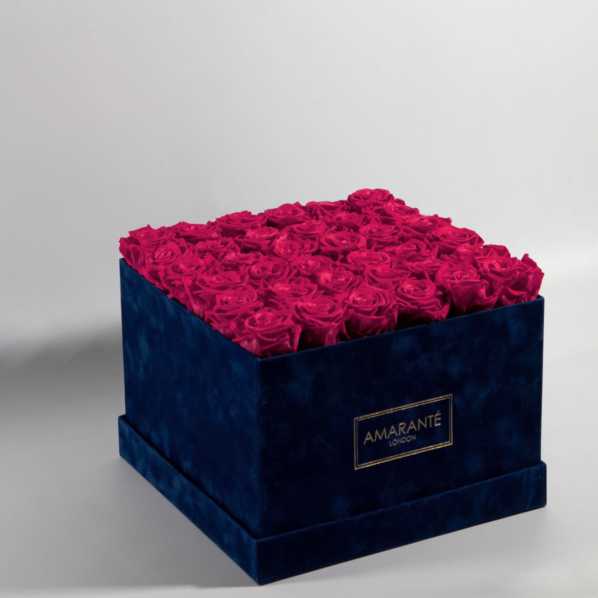 Majestic hot pink Roses in a dapper blue package, connoting playfulness, happiness, and joy. 