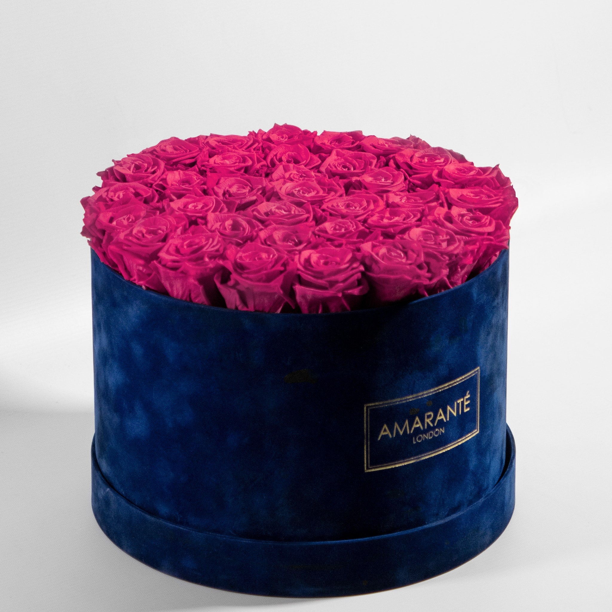 Eye catching hot pink roses in a dark blue box, ideal for adding a hint of playfulness to a tender and elegant gift. 